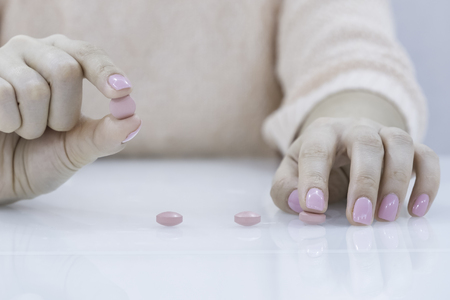 Close up young woman pours the pills out of the bottle. Medicine and health care concept. Birth control , Contraceptive, Vitamin, against menstrual pain.の写真素材