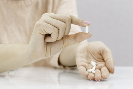 Close up young woman pours the pills out of the bottle. Medicine and health care concept.の写真素材