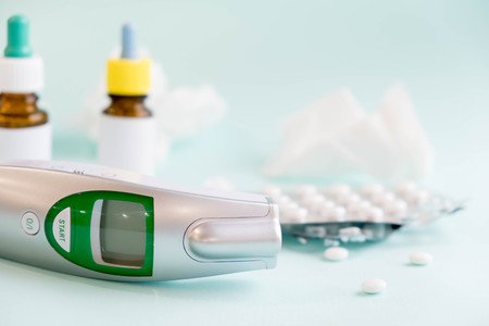 Spray for the nose or a pill to treat colds and gripes. Glass Bottle with medicines and paper handkerchiefs on a green background. Copy space for textの写真素材