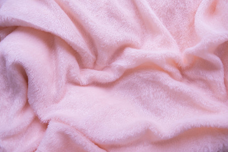 The blanket of furry pink fleece fabric. A background of light pink soft plush fleece material with a lot of relief foldsの写真素材