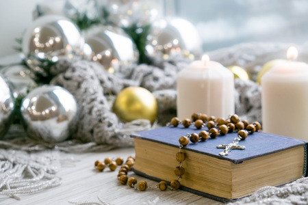 White holiday candles glowing behind wooden cross with red hearts in snow by antique rustic wood background; Christmas, Easter and religious background with copy spaceの写真素材