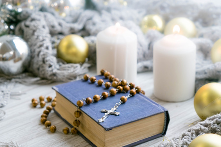 White holiday candles glowing behind wooden cross with red hearts in snow by antique rustic wood background; Christmas, Easter and religious background with copy spaceの写真素材