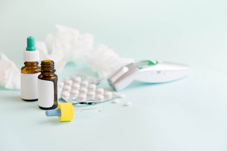 flu treatments. Spray for the nose or a pill to treat colds and gripes. Glass Bottle with medicines and paper handkerchiefs on blue background. Copy space for text. mockup, Top view. flat lay.の写真素材