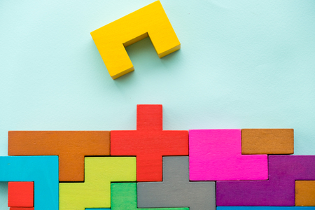 Different colorful shapes wooden blocks on beige background, flat lay. Geometric shapes in different colors, top view. Concept of creative, logical thinking or problem solving. Copy space.の写真素材