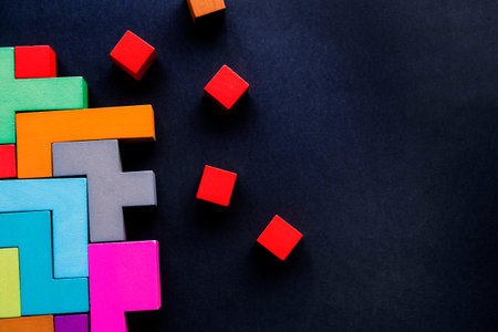 Different colorful shapes wooden blocks on black background, flat lay. Geometric shapes in different...