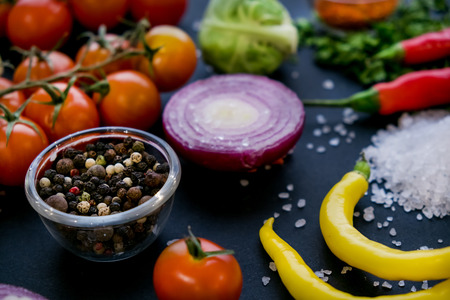 Close up of colorful spices and fresh vegetables for cooking on dark metal background with space for text. Top view. Bio Healthy food ingredients.の写真素材