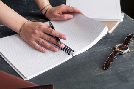 Selective focus table : Businessman hand write notebook, mobile phone, laptop, and pen on the wooden...