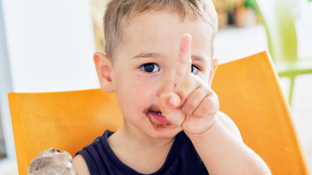 Cute kid having chocolate ice cream. two year old child