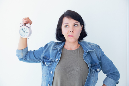 Asian woman holding a pink alarm clock on a white background. the concept of time management. get control of your lifeの写真素材
