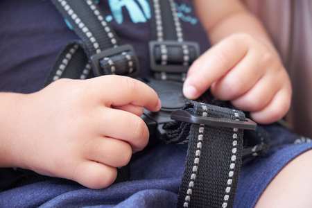 safety belt in the baby stroller, a small child tries to undo the lockの写真素材