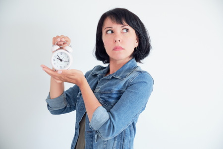 Surprised young woman with clock wondering eyes. stressed conceptの写真素材