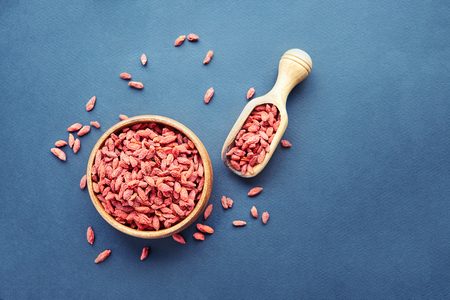 Goji in bowl on wood table. Top view of fresh goji in scoop and bowl. Goji in heart shape on table.の写真素材