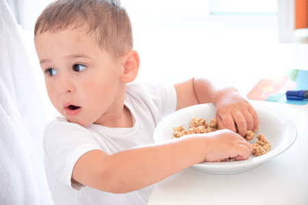 little boy helps dad pour milk into oatmeal. Quick Breakfast at homeの写真素材