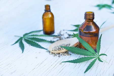 hemp leaves on wooden background, seeds, cannabis oil extracts in jarsの写真素材