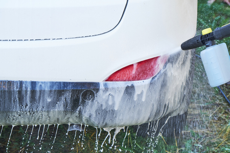 Shot of a man washing his car under high pressure water outdoors.の写真素材
