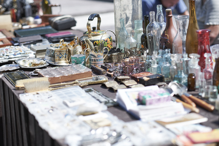 Market boot with objects beeing selled at the weekend flea market in the city center. Curious visitors in the backgroundの写真素材