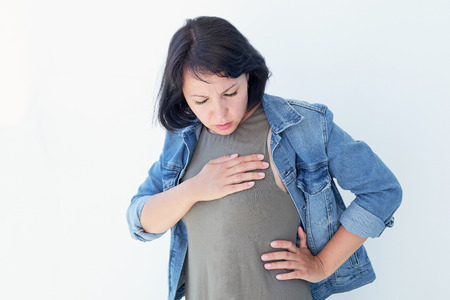 Aches and pains concept. Sick woman having bad ache and pain heart attack health problem. Female placing hands on her chest.の写真素材