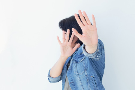 Young woman covering her face with palm saying no. Girl denying proposal, making stop gesture with her hand. Studio shot, copy spaceの写真素材