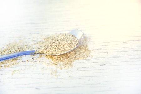 Amaranth seeds in a spoon on a wooden background.の写真素材