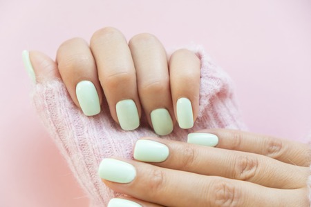 Tender hands with perfect blue manicure on trendy pastel pink background. Place for texの写真素材