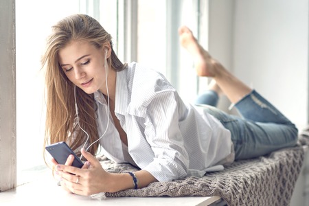 young beautiful woman listens to music through headphones on her phone. digital detox conceptの写真素材