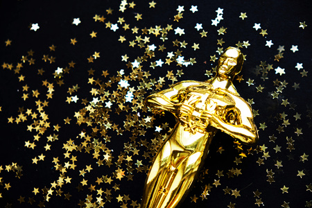 gold statue trophy on a yellow background, symbol of the victory of the actor in his profession.の写真素材