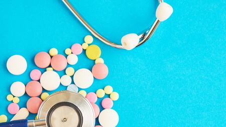 medication and a stethoscope on a blue background. free space for text. safe drugsの写真素材