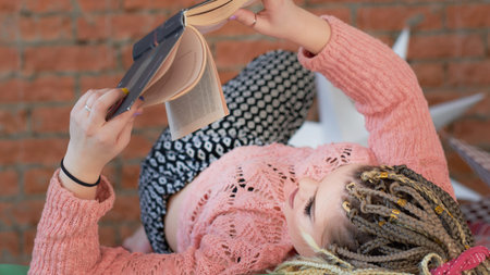 young frivolous girl lying on the bed and reading an art book. romantic feminine braz