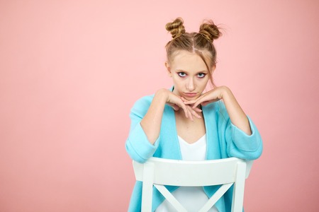 happy young girl model posing in studio on a pink background in spring clothes. fashion for teens, bright colors. turquoise coatの写真素材