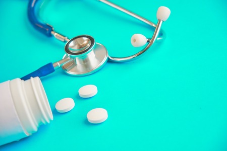 Aspirin and stetaskop on a blue background. white pills. how to get a drugの写真素材
