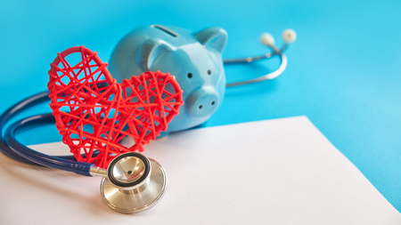 Piggy bank with stethoscope isolated on blue background. tax offset concept. Medical Expense Deductions and Tax Breaksの写真素材