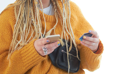 Extravagant plus size young woman with glasses holding a smartphone and a credit card in her hands....