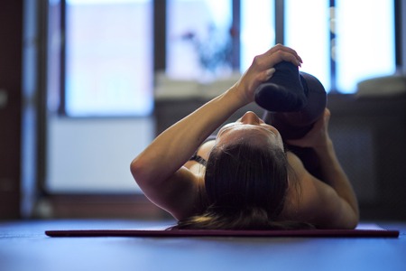 girl doing physical exercise and stretching legs on a mat, foot close up, healthy lifestyle concept. Side view of attractive young woman doing core exercise on fitness mat in the gymの写真素材