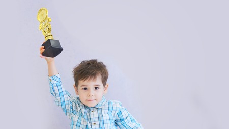 funny boy age three years old, holding in holding a trophyの写真素材