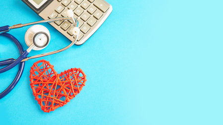 red heart and calculator with stethoscope isolated on blue background. tax offset concept. Medical Expense Deductions and Tax Breaks. affordable care act. high cost health careの写真素材