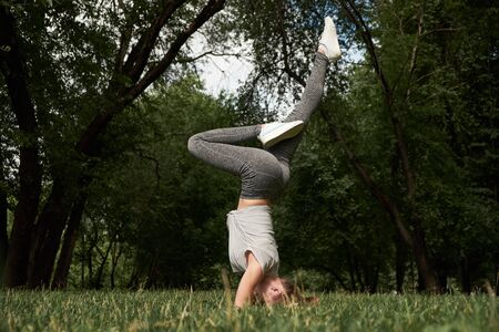Beautiful sporty fit yogi woman practices yoga handstand asana Bhuja Vrischikasana - Scorpion handstand pose.の写真素材