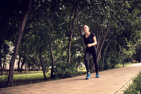 Photo of amazing young sports woman in park outdoors make sport stretching exercises.