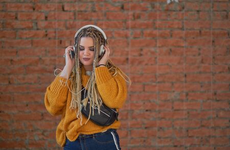 Nice young girl in headphones laughing looking at camera over Brick wall background.の写真素材