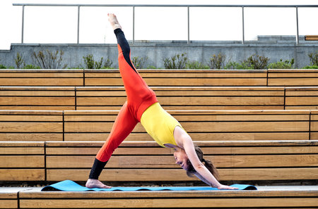 Young woman exercise yoga in the city hands up and balancing standing on one leg in sunny day.