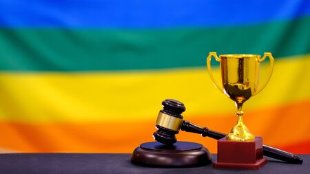 Judge's gavel and trophy on flag LGBT. Symbol for jurisdiction. Law concept a wooden judges gavel on table in a courtroom orの写真素材