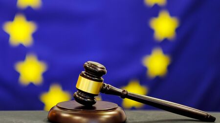 Judges gavel. Symbol for jurisdiction. Law concept a wooden judges gavel on table in a courtroom or law enforcement office on blue background. european union flag background.の写真素材