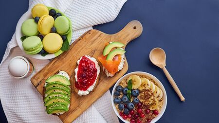 breakfast top view black background. oatmeal with berries, toasts on a wooden tray, nuts, coffee.の写真素材