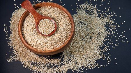 White quinoa seeds on a black background. quinoa on kitchen table top view. Healthy and diet superfood product.の写真素材