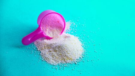 Measuring scoop with laundry powder on multi-colored background.の写真素材