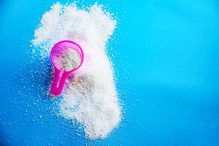 Measuring scoop with laundry powder on multi-colored background.の写真素材
