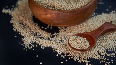 White quinoa seeds on a black background. quinoa on kitchen table top view. Healthy and diet superfood product.の写真素材