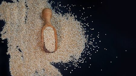 White quinoa seeds on a black background. quinoa on kitchen table top view. Healthy and diet superfood product.の写真素材