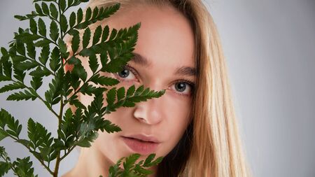 Natural organic skin care, the concept of harmony with nature, green long fern leaves grass near the face. portrait of beauty ladies. Young beautiful woman with clean sparkling skin of face and body.の写真素材