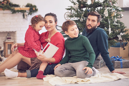 family brother sister and parents sit on the floor open Christmas presents. Family holidays. happy...