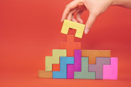 Hand holding piece of wooden block puzzle. wood cube stacking. Concept of complex and smart logical thinking. Slightly defocused and close up shot.の写真素材